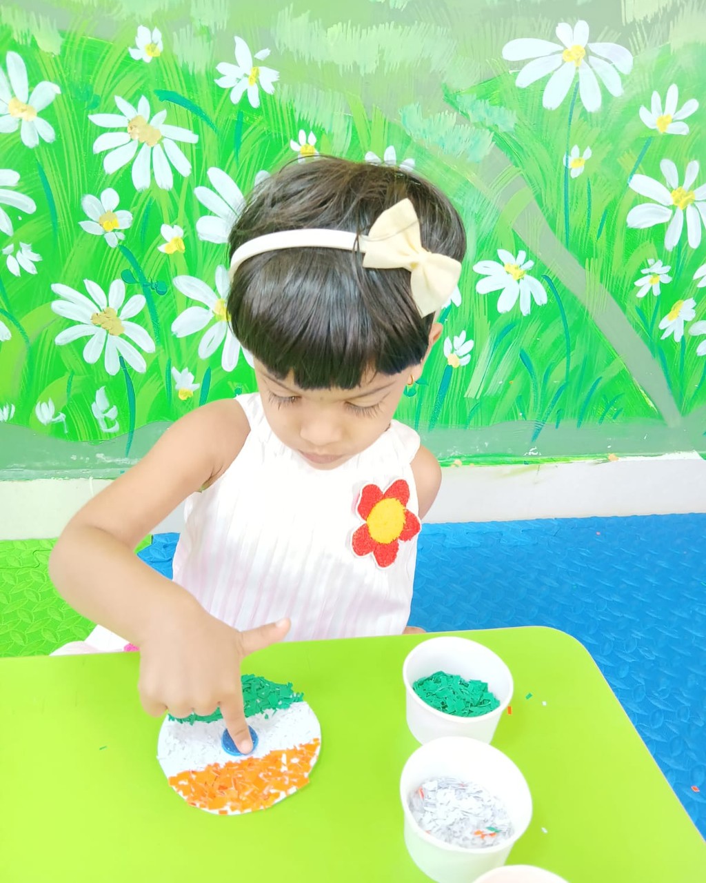 A young child creating an Indian flag craft with coloured paper pieces during a hands-on Montessori activity