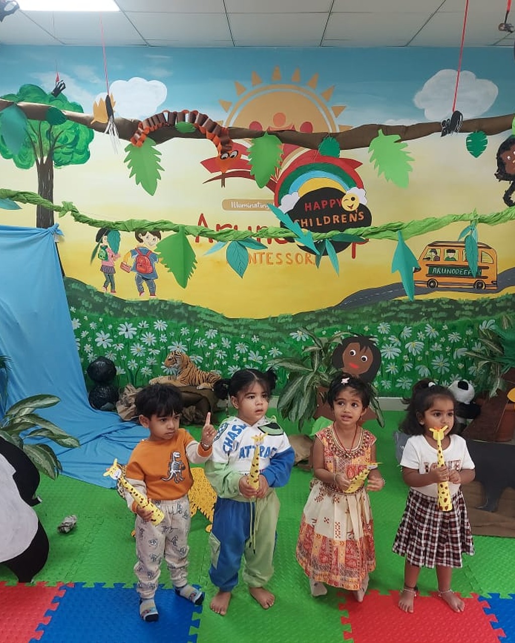 Four young children enjoying a jungle-themed Children's Day celebration in a bright Montessori classroom