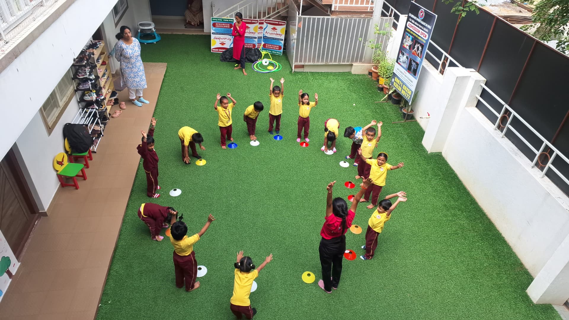 Children exercising with their teachers on the green outdoor play area